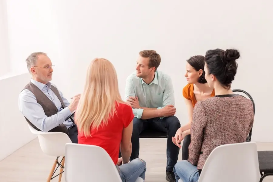 Individuals in group therapy looking at their instructor during an IOP vs OP session