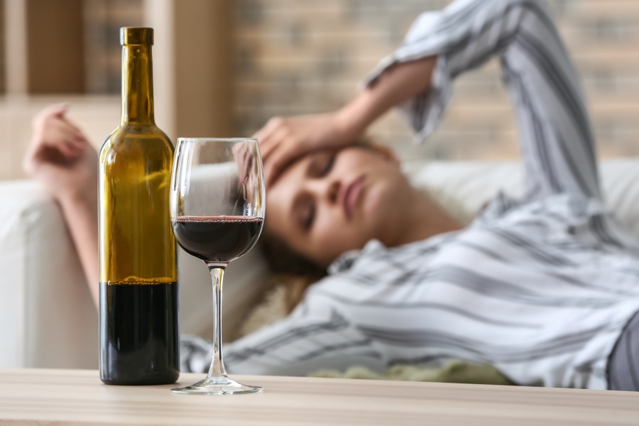 alcohol-consumption-gender-differences woman lying down after drinking wine, struggling with addiction