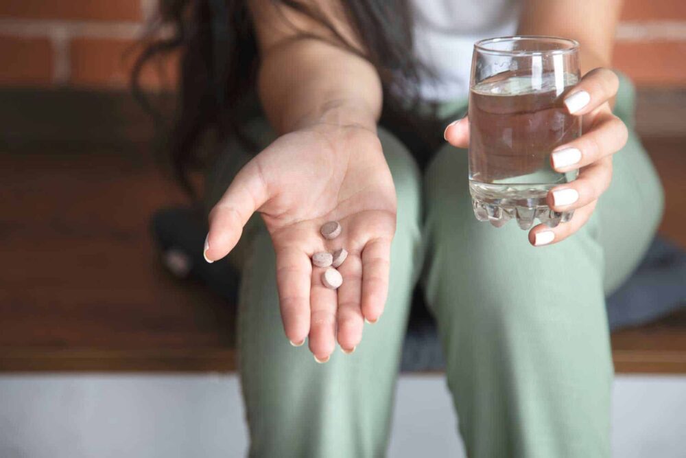 a-woman-holding-her-hand-out-with-pills